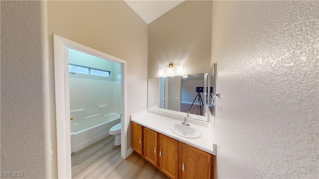 full bathroom with vaulted ceiling, toilet, shower / tub combination, vanity, and hardwood / wood-style flooring