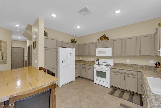 kitchen featuring gray cabinetry, light stone counters, and white appliances