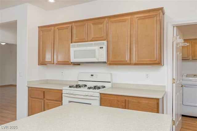 kitchen featuring recessed lighting, light countertops, light wood-style floors, washer / dryer, and white appliances