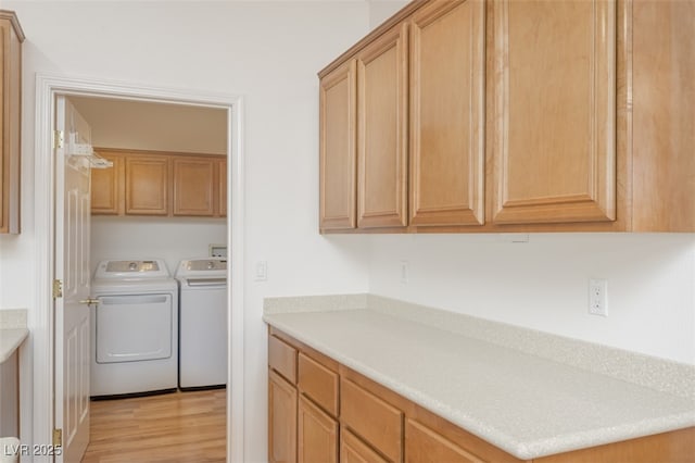 washroom featuring light wood-type flooring, cabinet space, and washing machine and clothes dryer