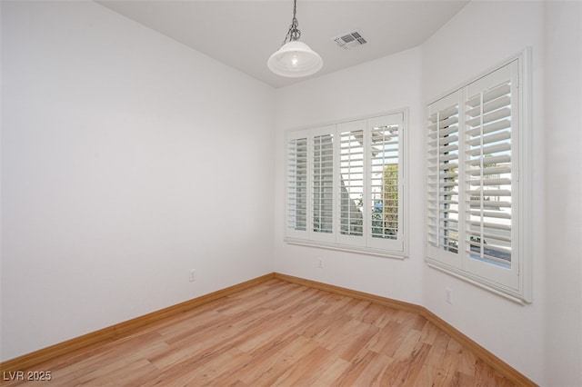 spare room with baseboards, visible vents, and light wood finished floors