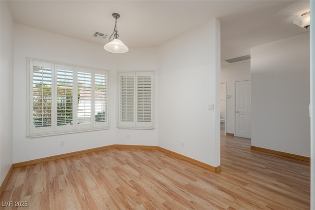 spare room with light wood-type flooring, visible vents, and baseboards