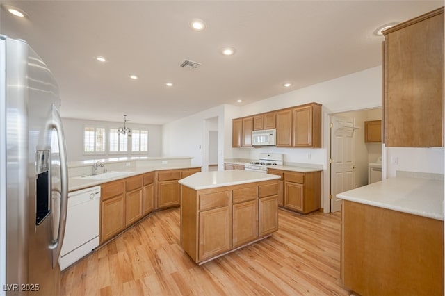 kitchen with light wood finished floors, light countertops, visible vents, a sink, and white appliances