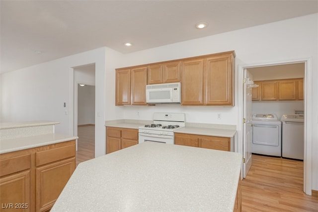 kitchen with white appliances, light wood-type flooring, washing machine and clothes dryer, and recessed lighting