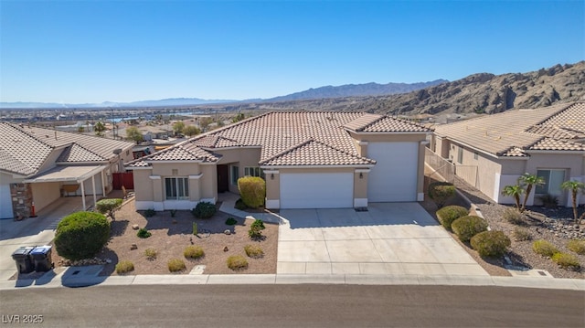 mediterranean / spanish-style house with a tile roof, stucco siding, an attached garage, a mountain view, and driveway