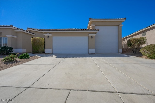 view of front facade featuring a garage, a tiled roof, driveway, and stucco siding