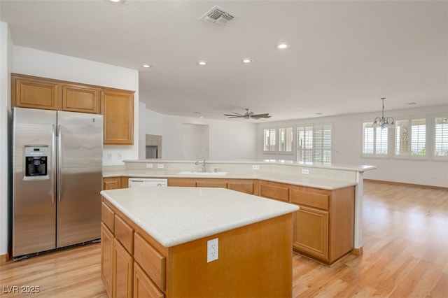 kitchen featuring light countertops, visible vents, a sink, and stainless steel refrigerator with ice dispenser