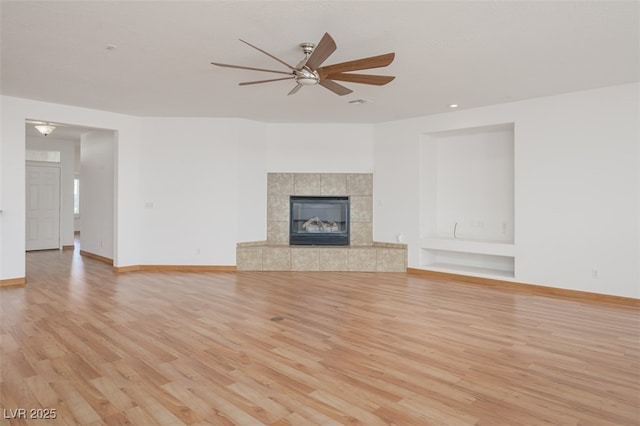 unfurnished living room with light wood-style floors, a fireplace, baseboards, and ceiling fan