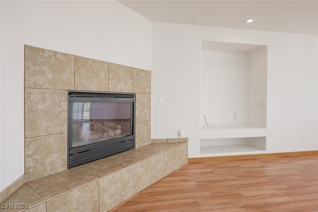 room details with a tiled fireplace, wood finished floors, and recessed lighting