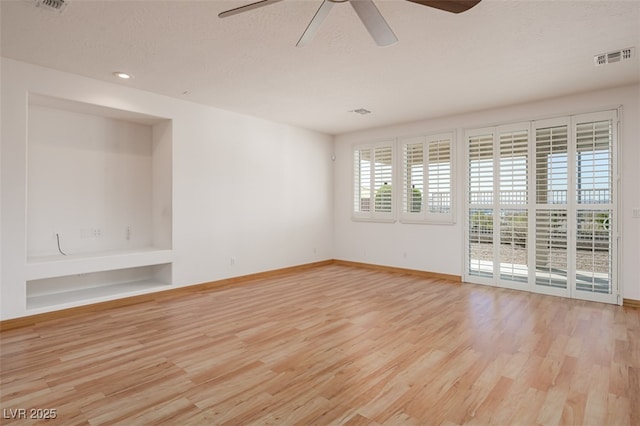 unfurnished room featuring baseboards, visible vents, a ceiling fan, wood finished floors, and a textured ceiling