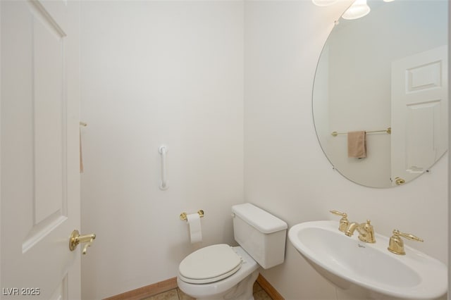 half bath with a sink, toilet, and baseboards