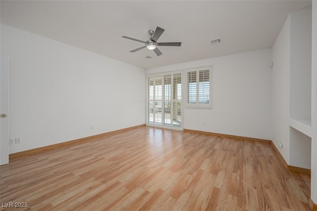 spare room featuring a ceiling fan, light wood-type flooring, visible vents, and baseboards