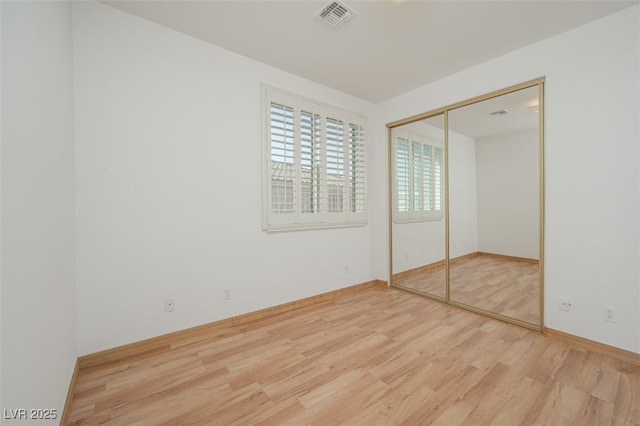 unfurnished bedroom featuring a closet, visible vents, and wood finished floors