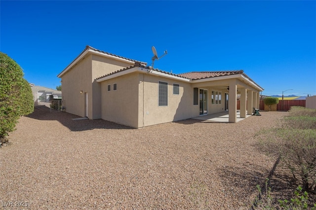 rear view of property with a patio, fence, a tiled roof, and stucco siding