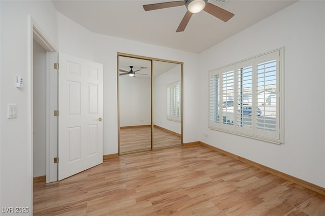 unfurnished bedroom with light wood-type flooring, a closet, ceiling fan, and baseboards