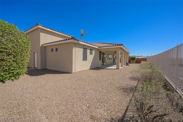 back of property with a patio area, a tile roof, a fenced backyard, and stucco siding