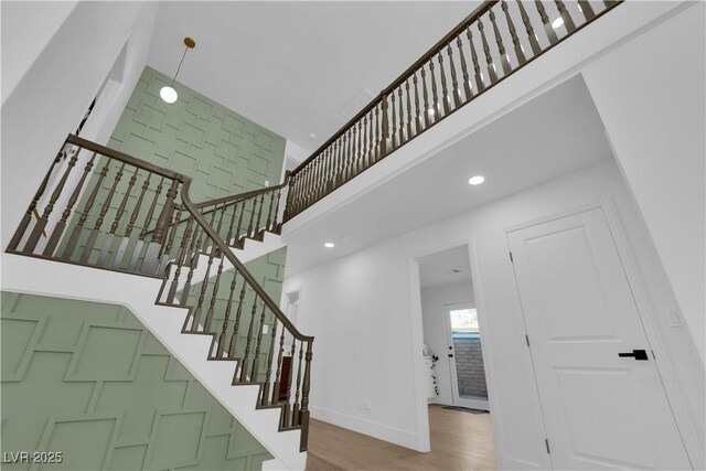 stairway featuring wood-type flooring and a high ceiling