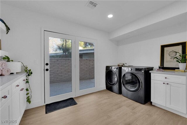 clothes washing area with cabinets, separate washer and dryer, and light wood-type flooring