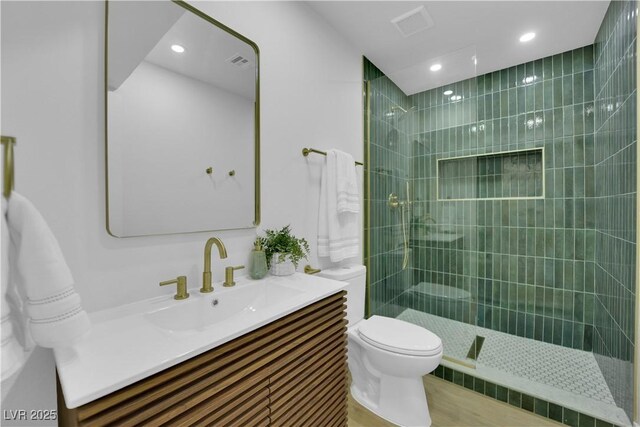 bathroom with vanity, tiled shower, and toilet