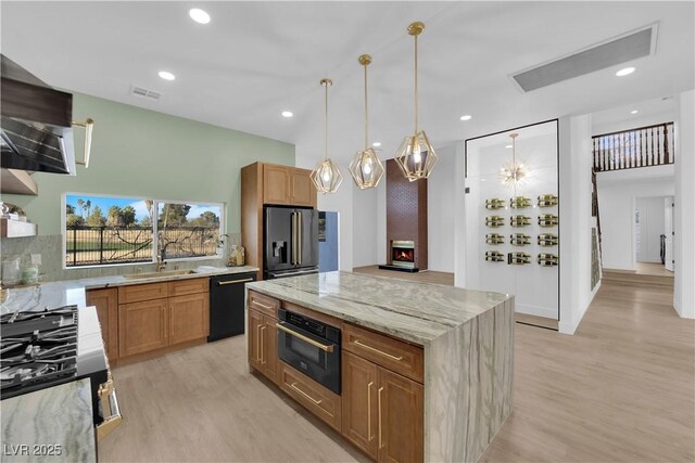 kitchen featuring sink, light stone counters, black appliances, light wood-type flooring, and backsplash