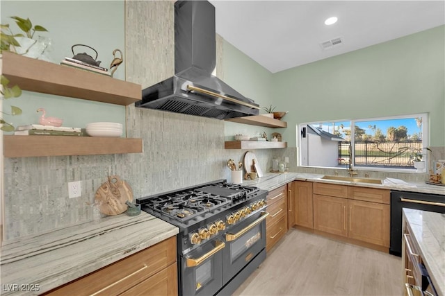 kitchen featuring range with two ovens, light wood-type flooring, dishwasher, decorative backsplash, and wall chimney range hood