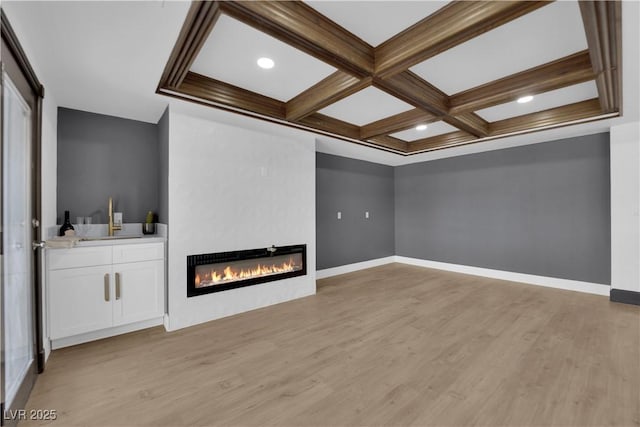 unfurnished living room with coffered ceiling, light hardwood / wood-style floors, and beam ceiling