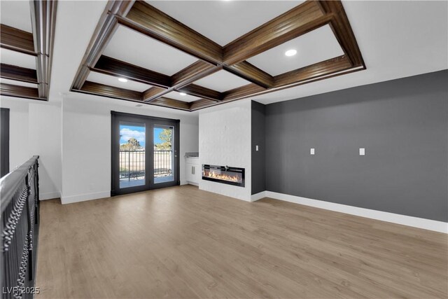 unfurnished living room featuring a fireplace, coffered ceiling, beam ceiling, and light hardwood / wood-style flooring