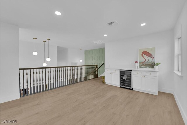 bar with pendant lighting, white cabinets, light wood-type flooring, and wine cooler