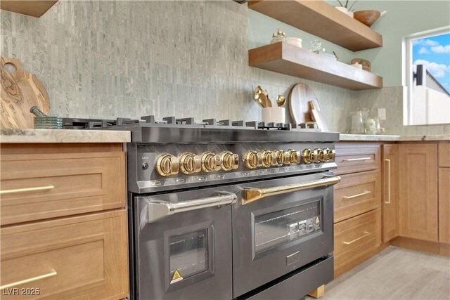 kitchen with backsplash, high end range, and light hardwood / wood-style floors