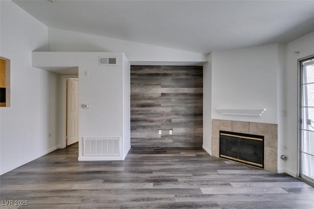 unfurnished living room with hardwood / wood-style flooring and a tiled fireplace