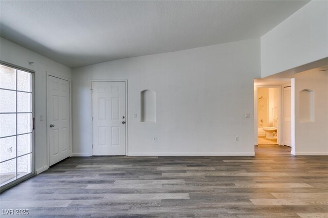 empty room featuring vaulted ceiling, hardwood / wood-style floors, and plenty of natural light