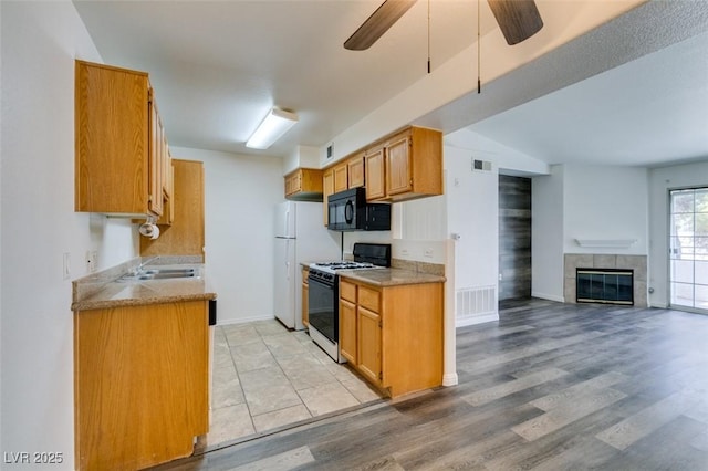 kitchen featuring a tile fireplace, ceiling fan, sink, light hardwood / wood-style floors, and white appliances