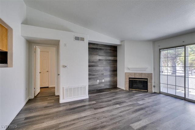 unfurnished living room with dark hardwood / wood-style flooring, vaulted ceiling, and a tiled fireplace