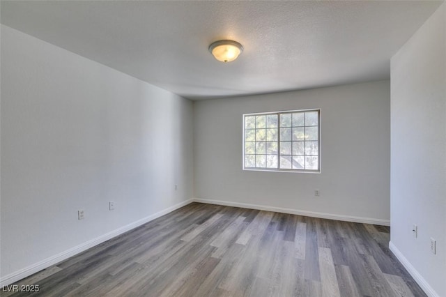 spare room featuring a textured ceiling and dark hardwood / wood-style floors