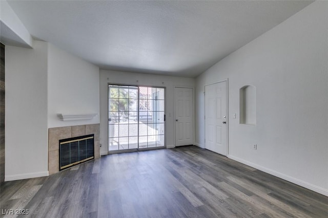 unfurnished living room with a tile fireplace, vaulted ceiling, and dark wood-type flooring