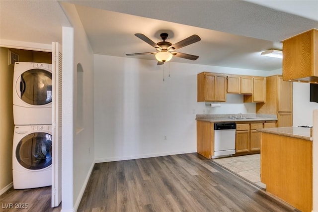 kitchen featuring white dishwasher, sink, ceiling fan, light wood-type flooring, and stacked washer / drying machine