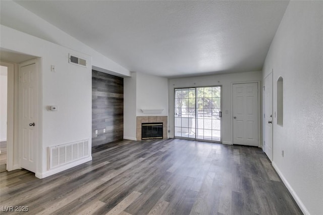 unfurnished living room featuring a textured ceiling, a fireplace, dark hardwood / wood-style floors, and lofted ceiling