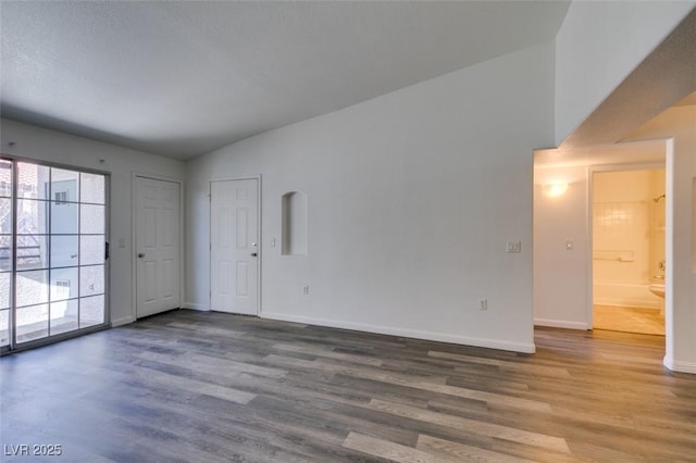 empty room with hardwood / wood-style flooring and lofted ceiling