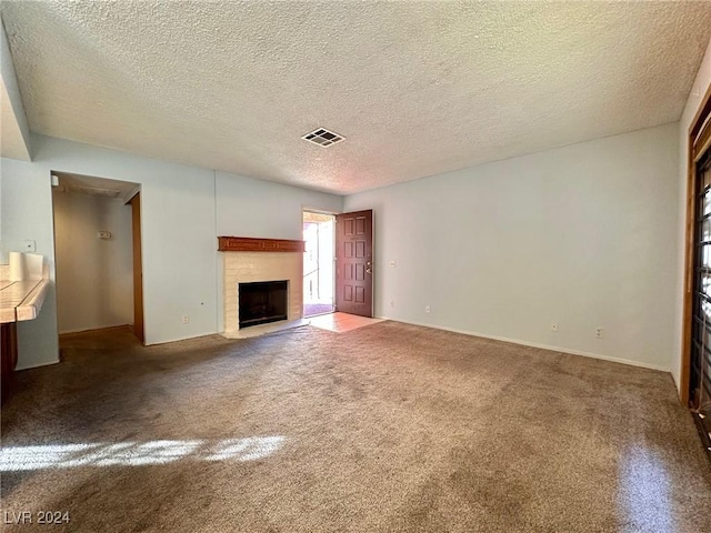 unfurnished living room with carpet flooring, a textured ceiling, and a brick fireplace