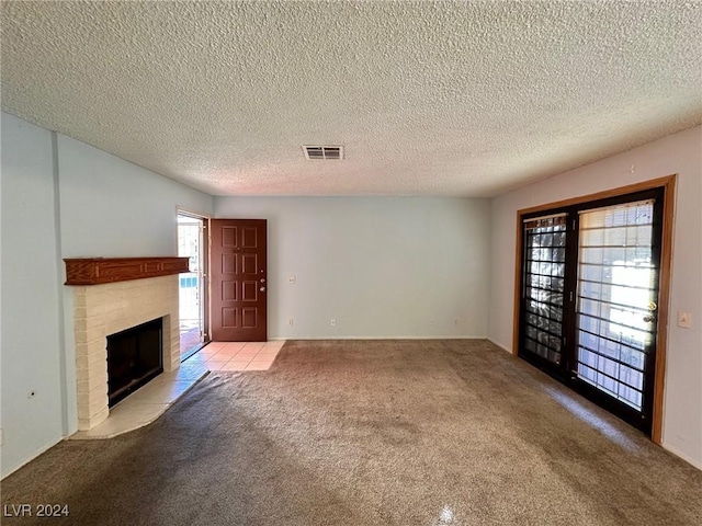 unfurnished living room featuring a textured ceiling, light colored carpet, and a brick fireplace