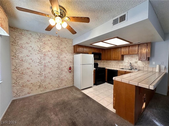 kitchen with black appliances, sink, light tile patterned floors, tile counters, and kitchen peninsula