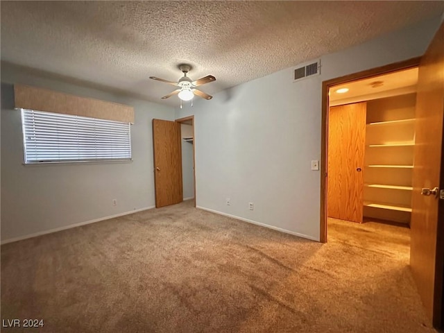 unfurnished bedroom featuring ceiling fan, light colored carpet, and a textured ceiling