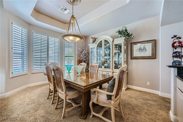 carpeted dining space featuring a tray ceiling