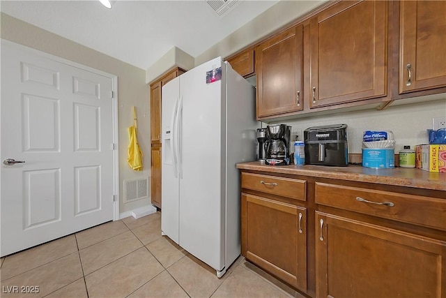 kitchen with white fridge with ice dispenser and light tile patterned floors