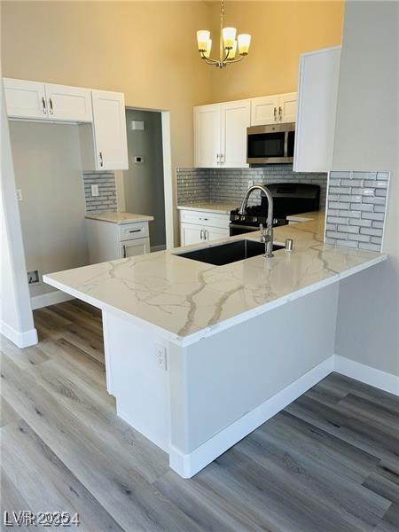 kitchen with white cabinetry, pendant lighting, kitchen peninsula, and a notable chandelier