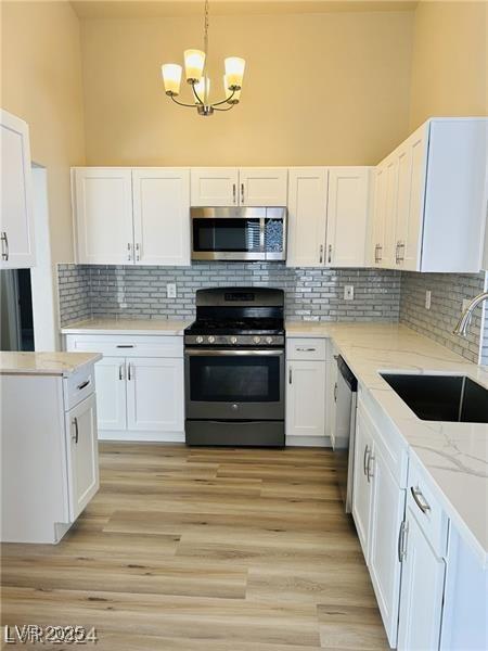 kitchen with white cabinetry, appliances with stainless steel finishes, tasteful backsplash, pendant lighting, and sink