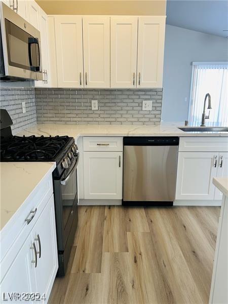 kitchen featuring tasteful backsplash, appliances with stainless steel finishes, sink, and white cabinetry