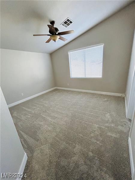 spare room featuring carpet, vaulted ceiling, and ceiling fan