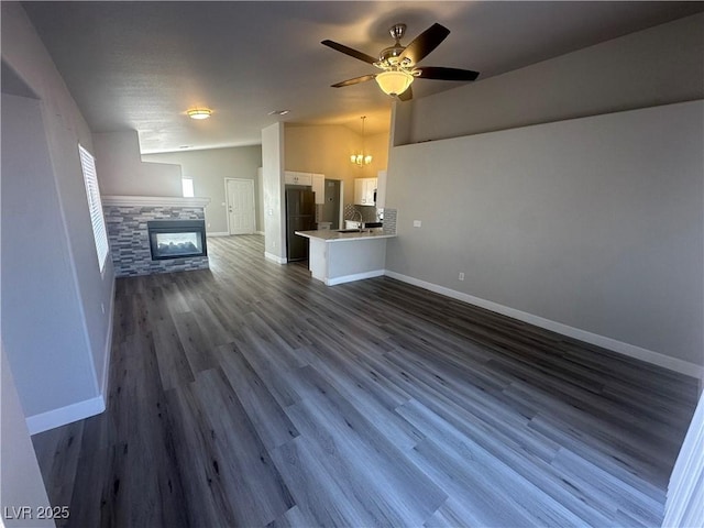 unfurnished living room featuring a fireplace, dark hardwood / wood-style flooring, and ceiling fan with notable chandelier