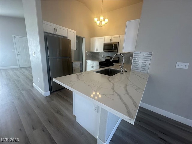 kitchen featuring decorative light fixtures, backsplash, kitchen peninsula, appliances with stainless steel finishes, and white cabinets